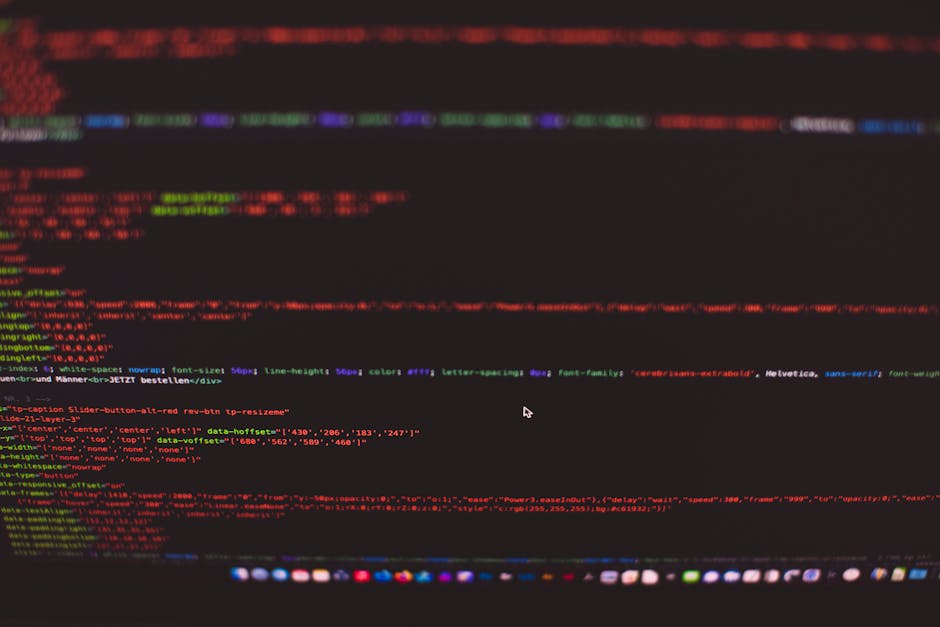 A close-up of a computer screen displaying lines of colorful code in red, green, purple, and blue on a dark background. The code appears to be HTML or CSS syntax, with tags, attributes, and values vis